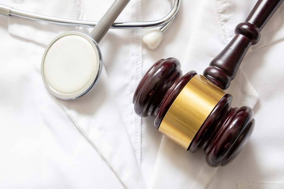 A wooden judge's gavel and a silver stethoscope resting together on a crisp white medical lab coat, featured image for the article Therapy for Healthcare Regulatory Attorneys.