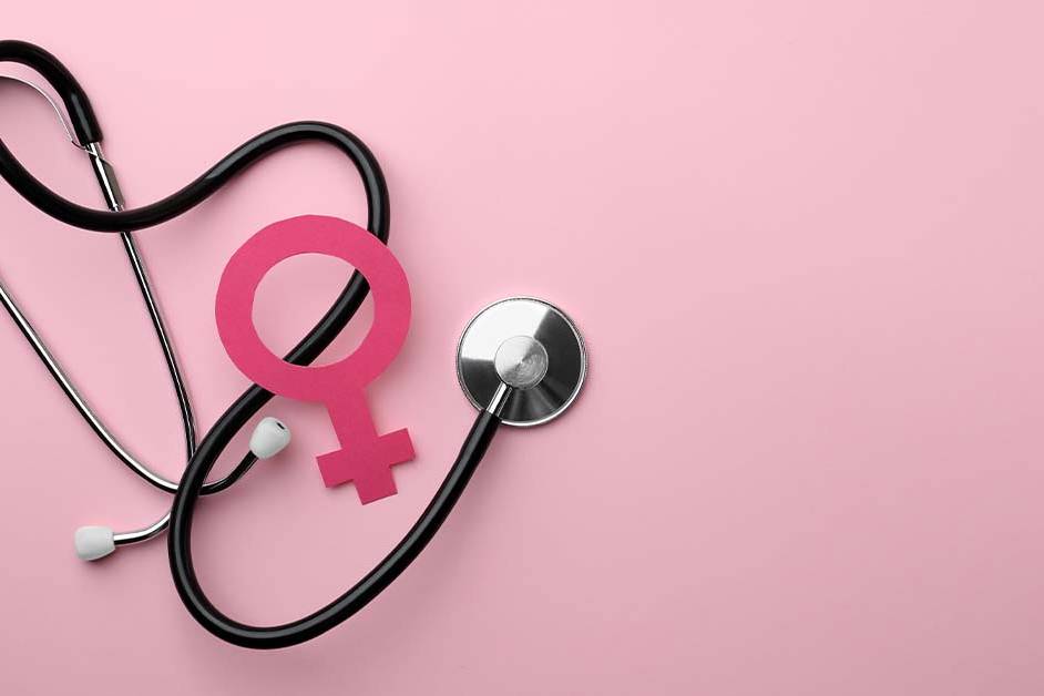 A black stethoscope arranged around a pink paper female gender symbol on a soft pink background, representing women's health and OB/GYN care.