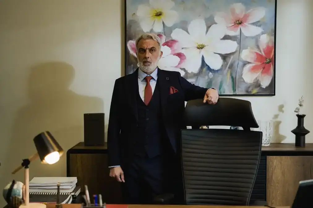 A senior leader reviewing notes at a clean desk in a modern corner office during the workday.
