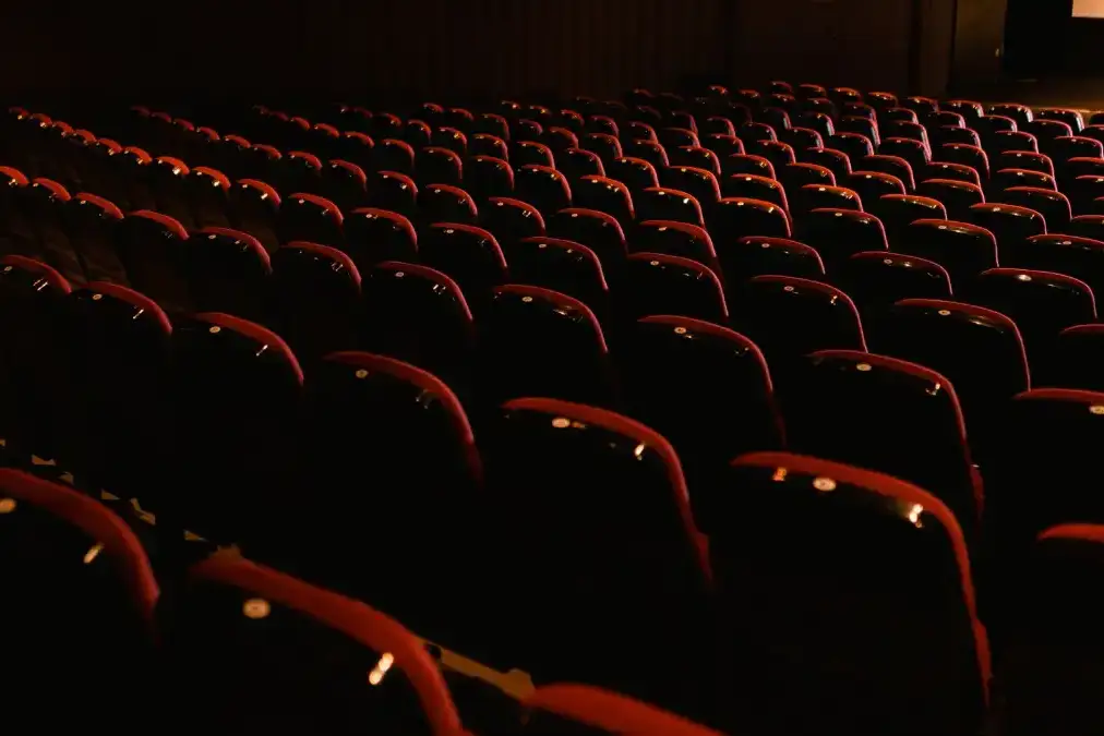 An entertainment executive alone in a quiet screening room, lit by the glow of a blank screen.