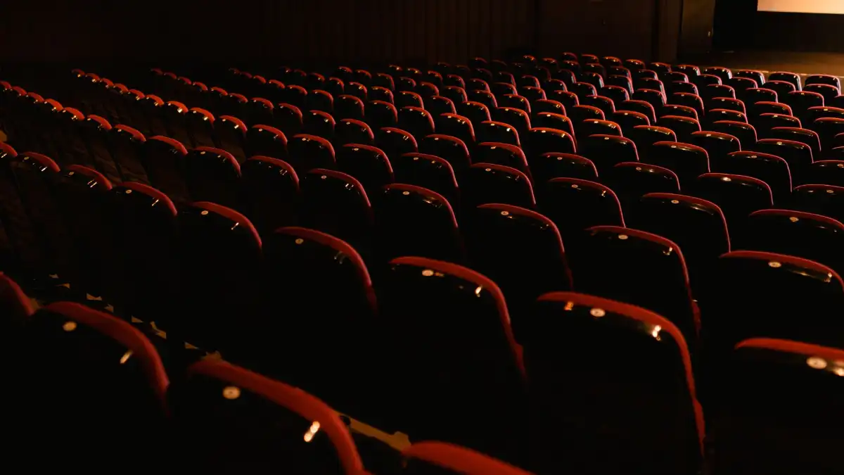 An entertainment executive alone in a quiet screening room, lit by the glow of a blank screen.