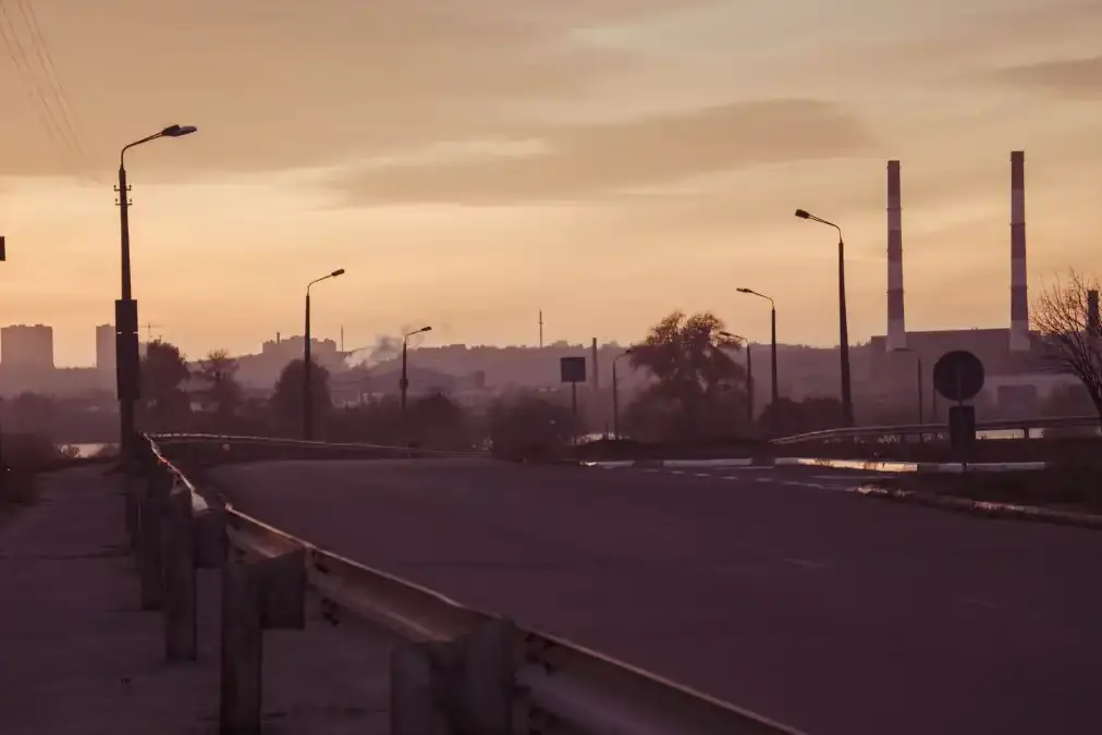 A senior police officer standing alone at dusk outside a quiet station, looking toward the horizon.