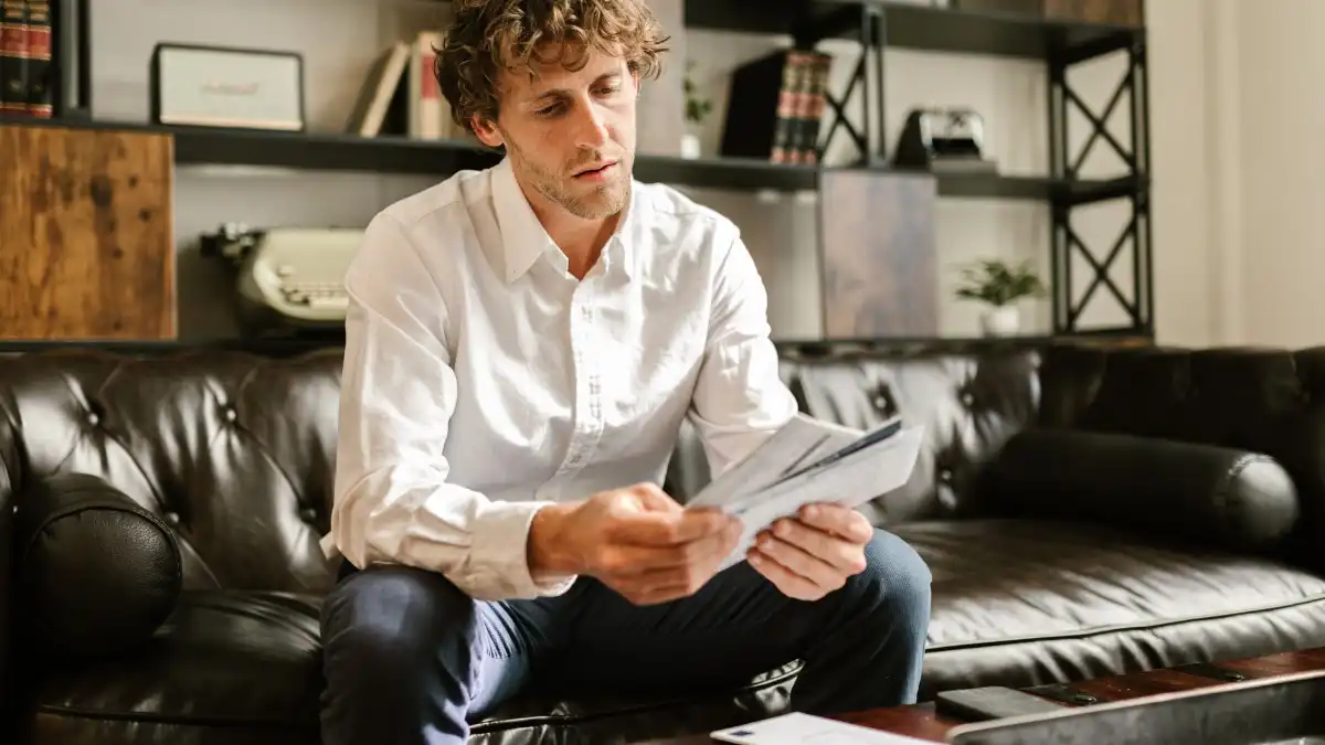 A professional reading a printed document at a calm home office desk, with a coffee cup nearby.
