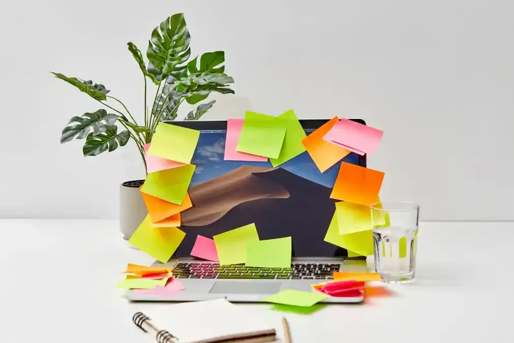 A focused executive at a busy desk with multiple screens and sticky notes, mid-thought during a workday.