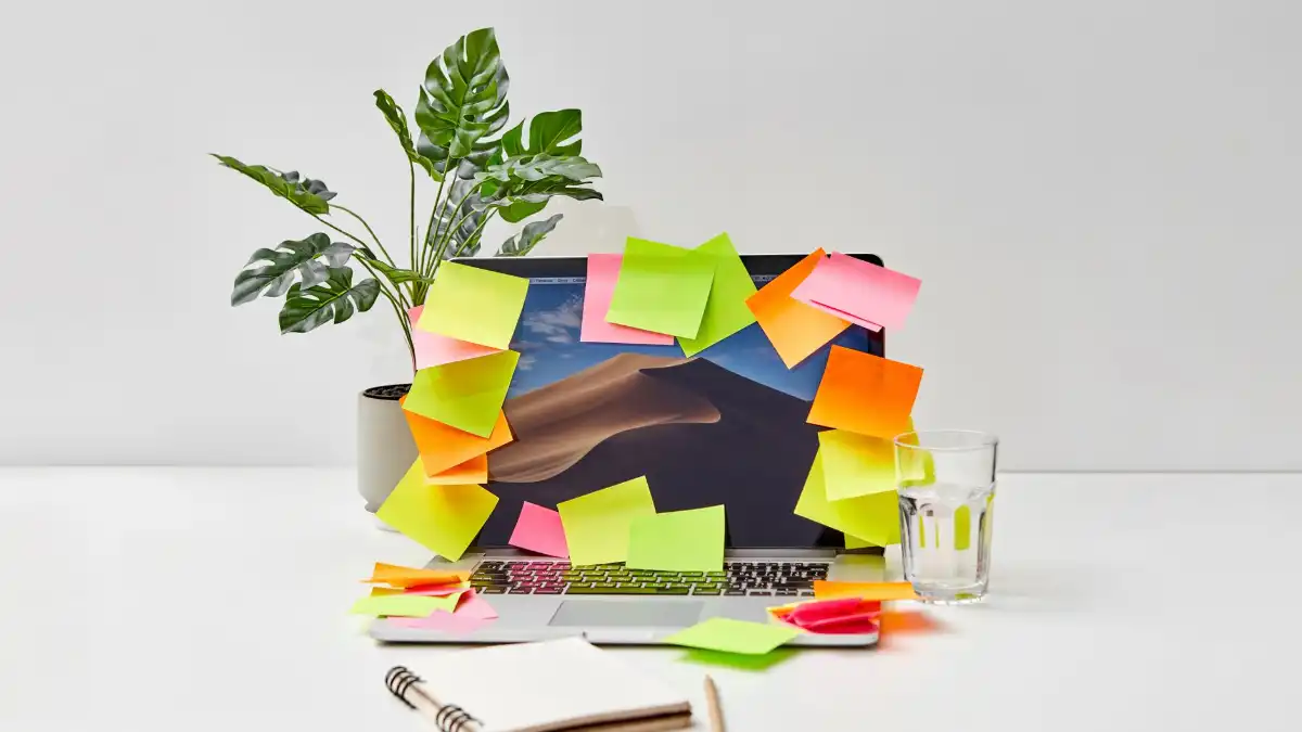 A focused executive at a busy desk with multiple screens and sticky notes, mid-thought during a workday.