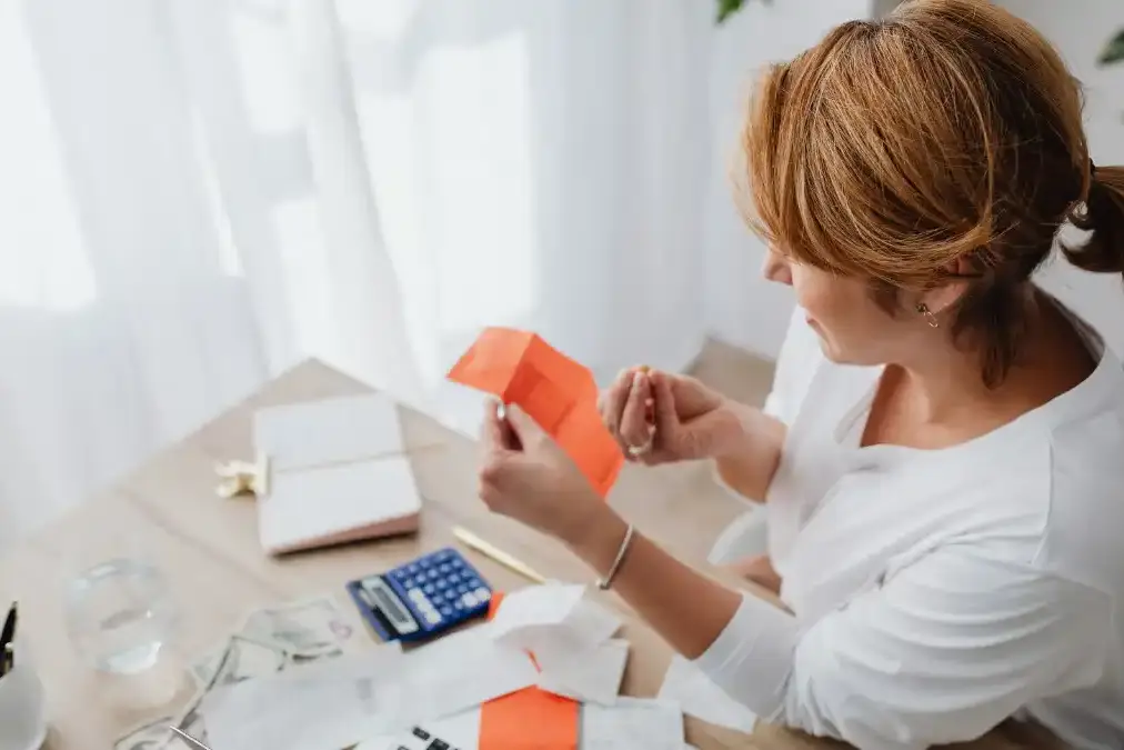 A person at a tidy home desk reviewing finance paperwork and a laptop while planning healthcare spending.