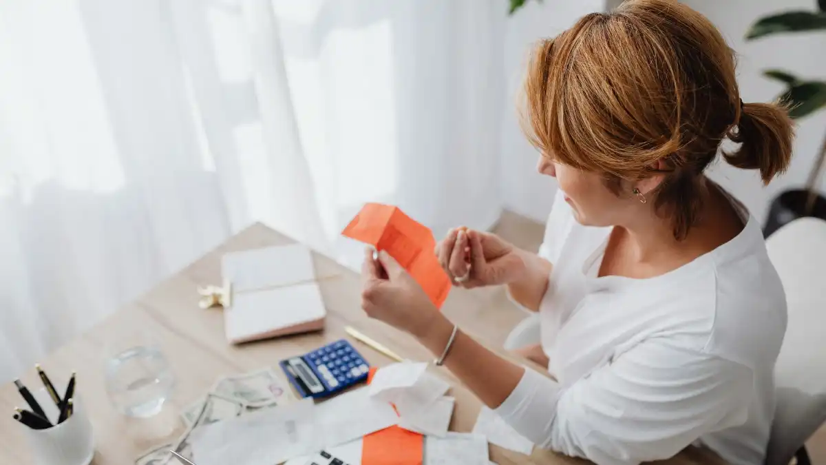 A person at a tidy home desk reviewing finance paperwork and a laptop while planning healthcare spending.