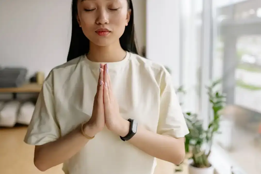 A person breathing slowly with eyes closed in a sunlit calm room, releasing built-up tension.