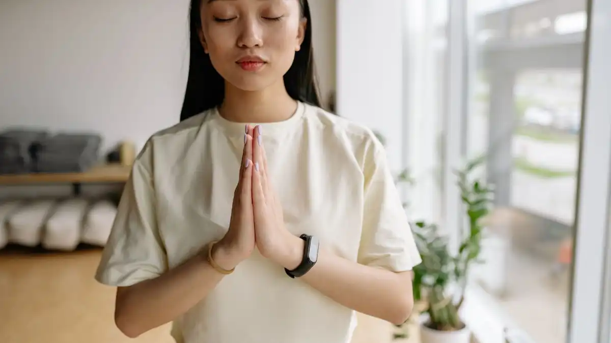 A person breathing slowly with eyes closed in a sunlit calm room, releasing built-up tension.