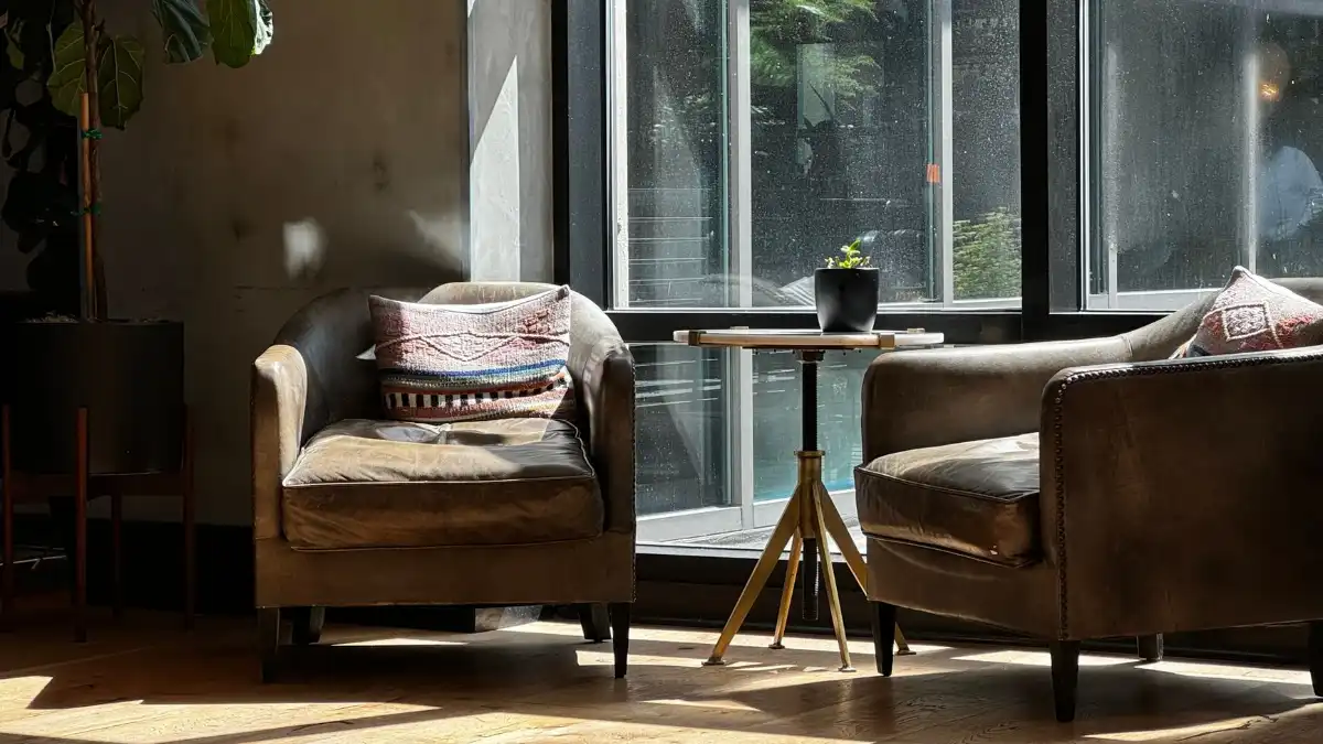Two empty comfortable chairs in a warm, unhurried therapy room with soft natural light.