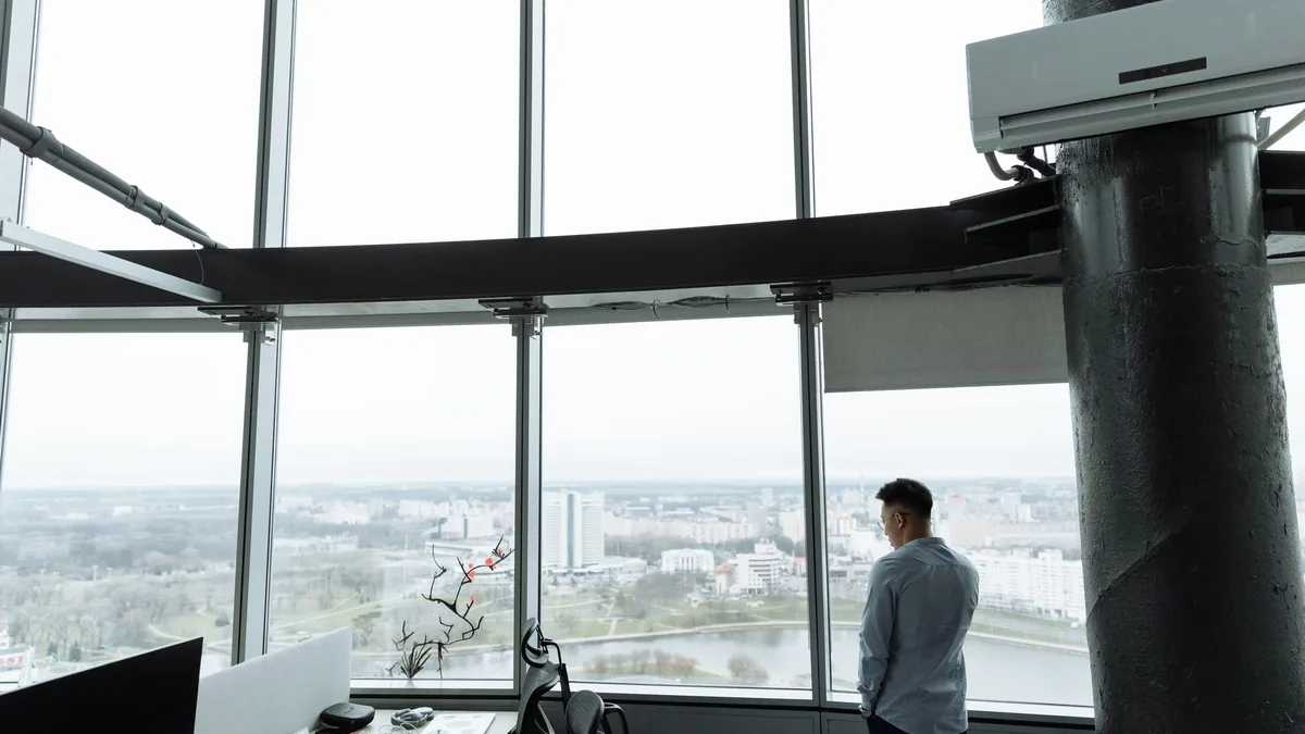 A senior executive standing alone by an office window at dusk