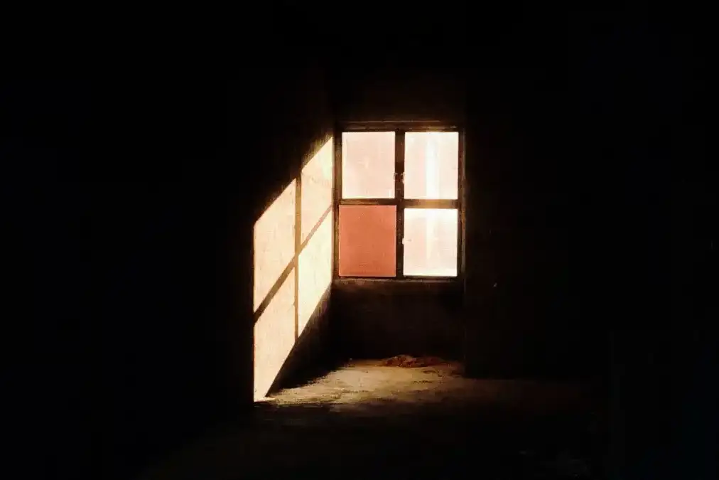 A tired professional pausing alone by a window after a long workday.
