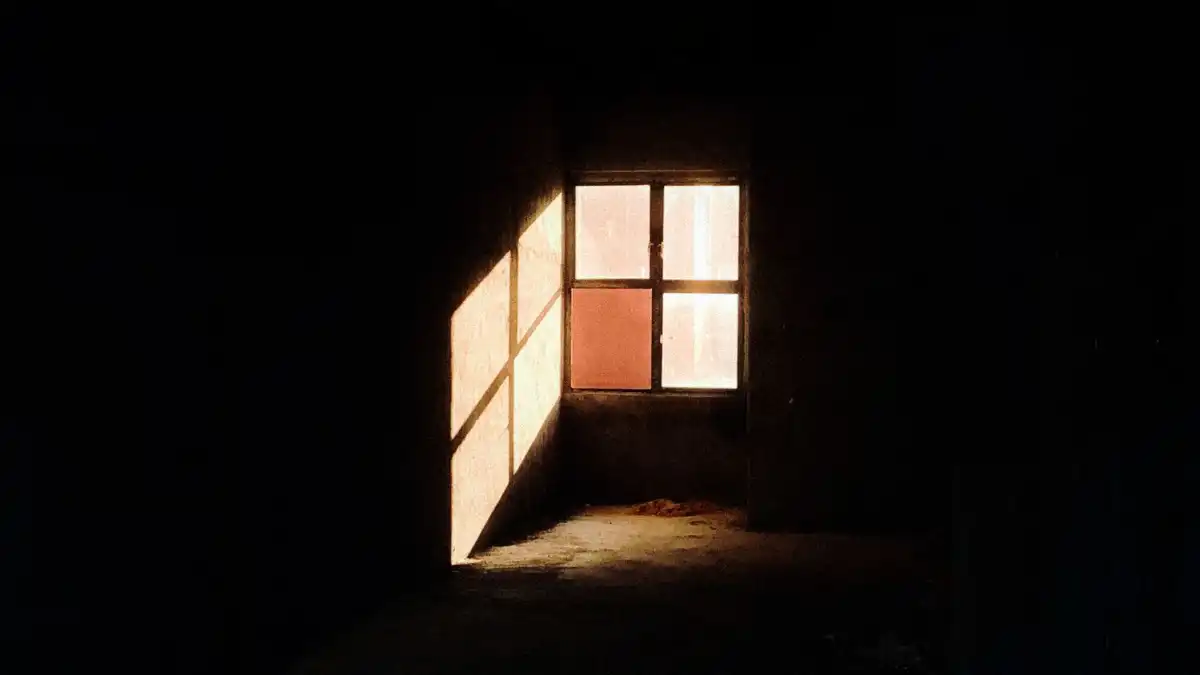 A tired professional pausing alone by a window after a long workday.