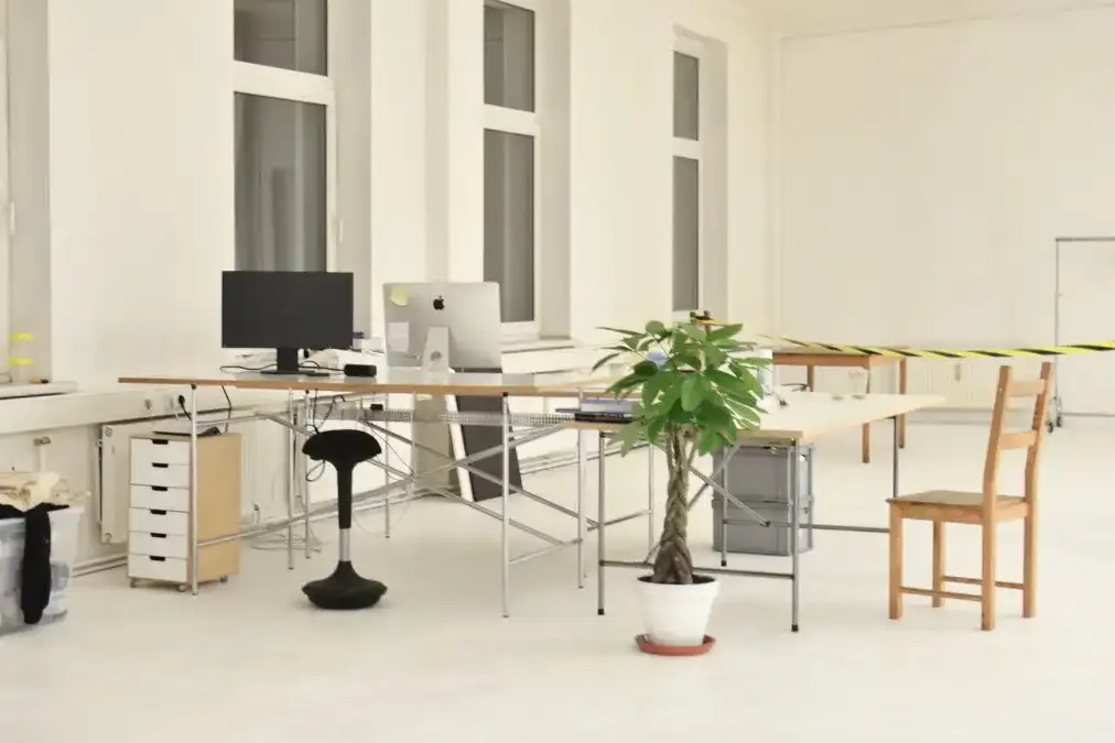 An architect standing alone reviewing drawings in a sunlit studio.