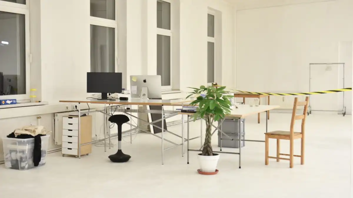 An architect standing alone reviewing drawings in a sunlit studio.