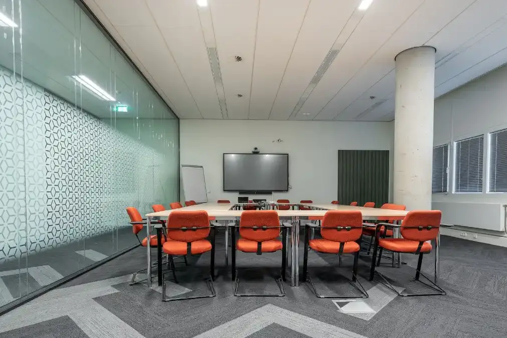 A director sitting alone in an empty boardroom looking out a window.