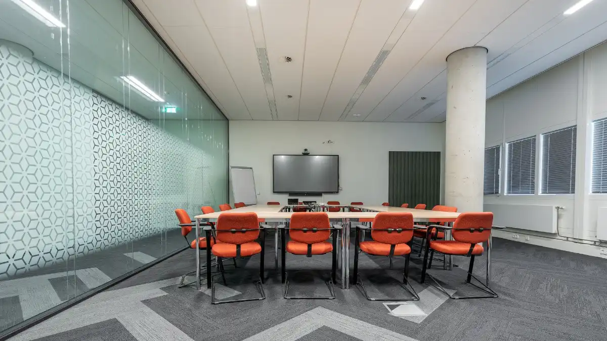 A director sitting alone in an empty boardroom looking out a window.