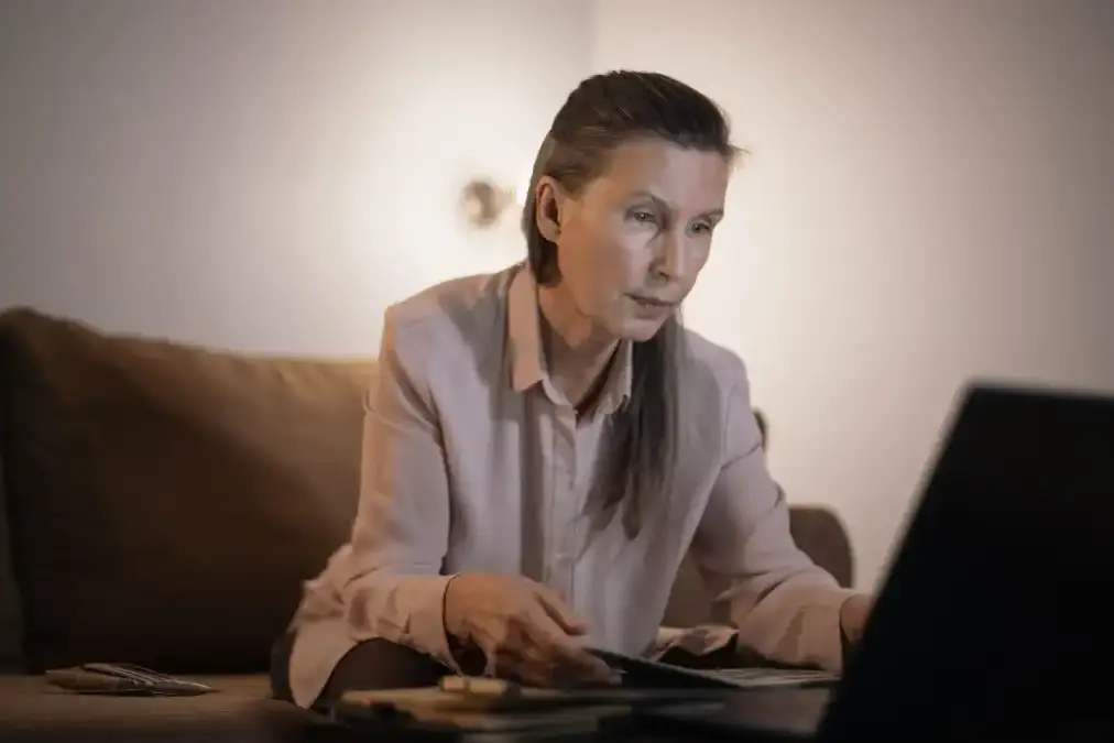 An executive sits alone in a dim study at night, wedding ring visible, looking down in quiet thought.