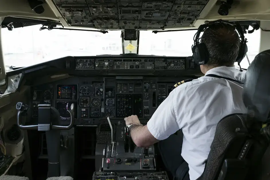 Pilot from behind flying the aircraft with hand on the throttle in the cockpit
