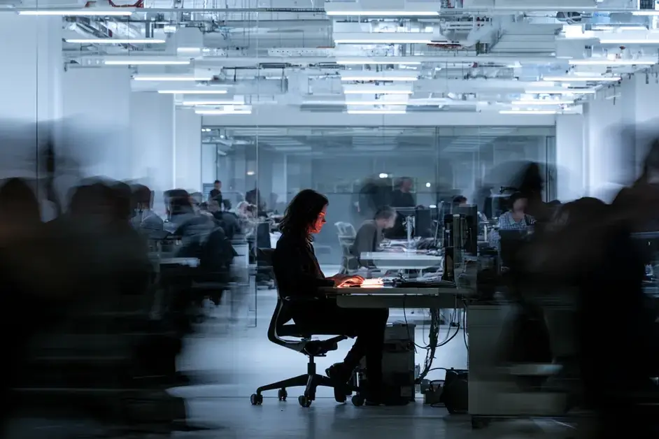 Long-exposure photo of a still, focused office worker surrounded by blurred, rushing colleagues